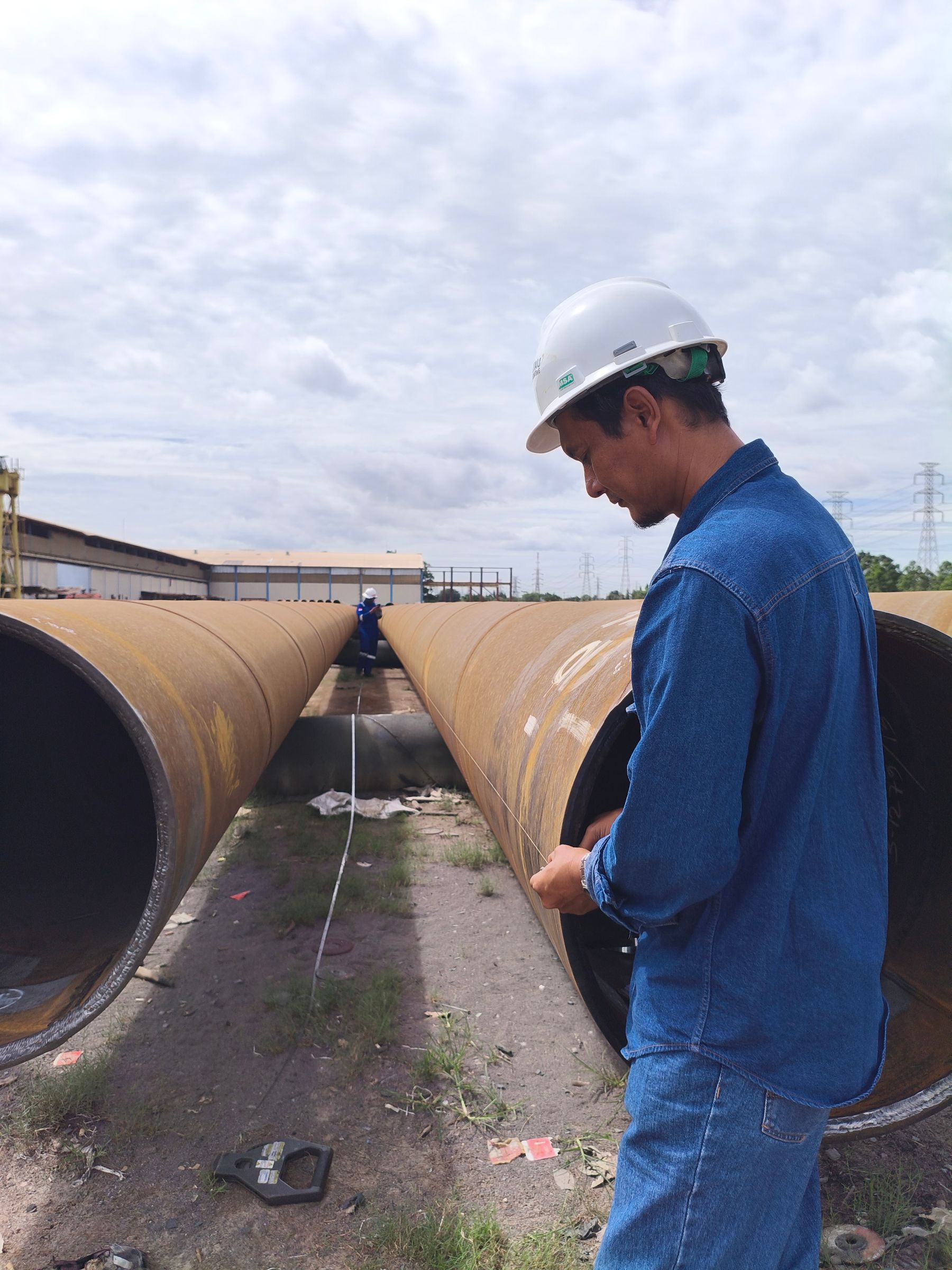 Inspector working alongside large industrial steel pipes